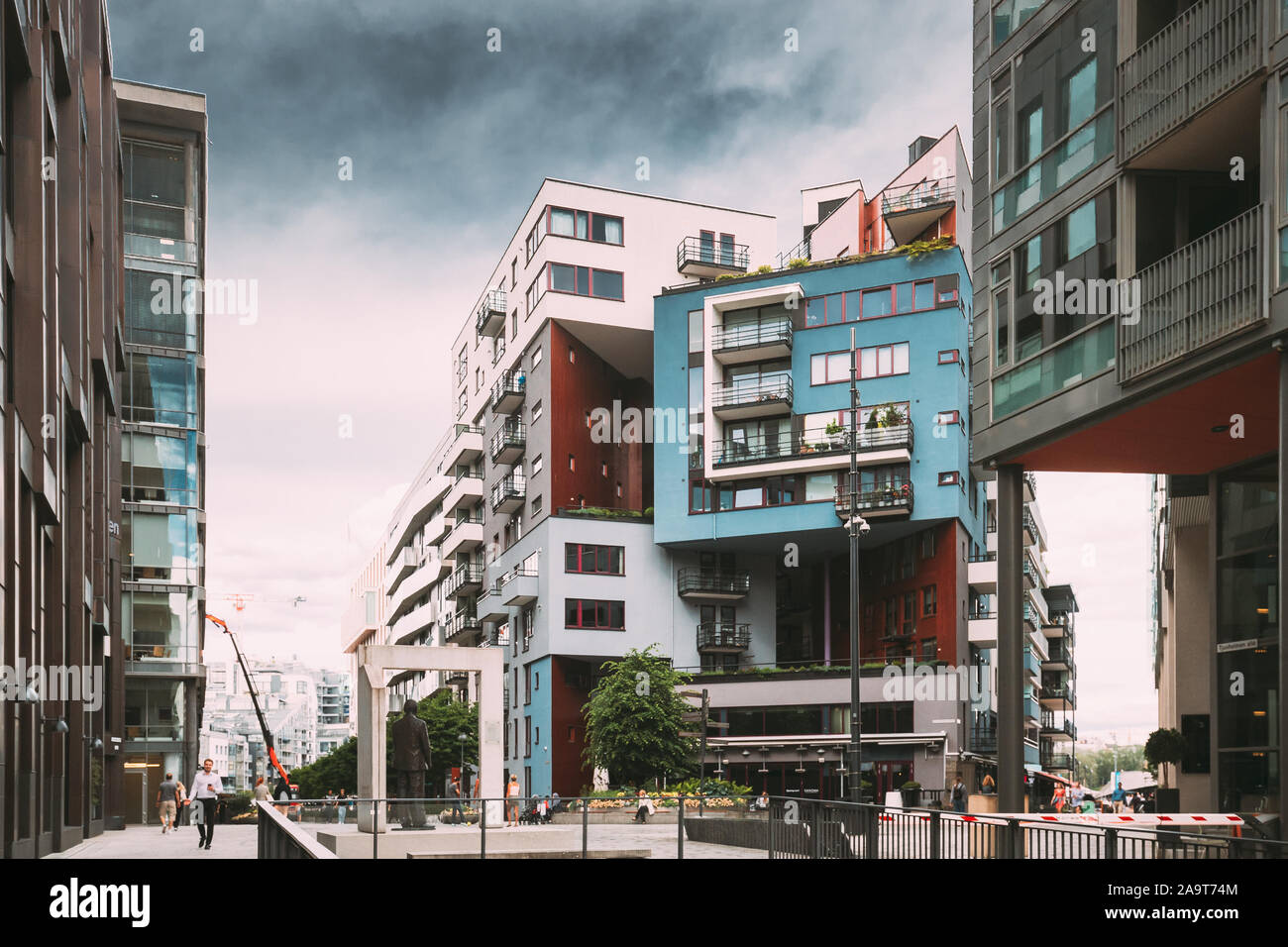 Oslo, Norway - June 24, 2019: People Walking Near Residential Multi-storey Houses In Aker Brygge District In Summer Evening. Famous And Popular Place. Stock Photo