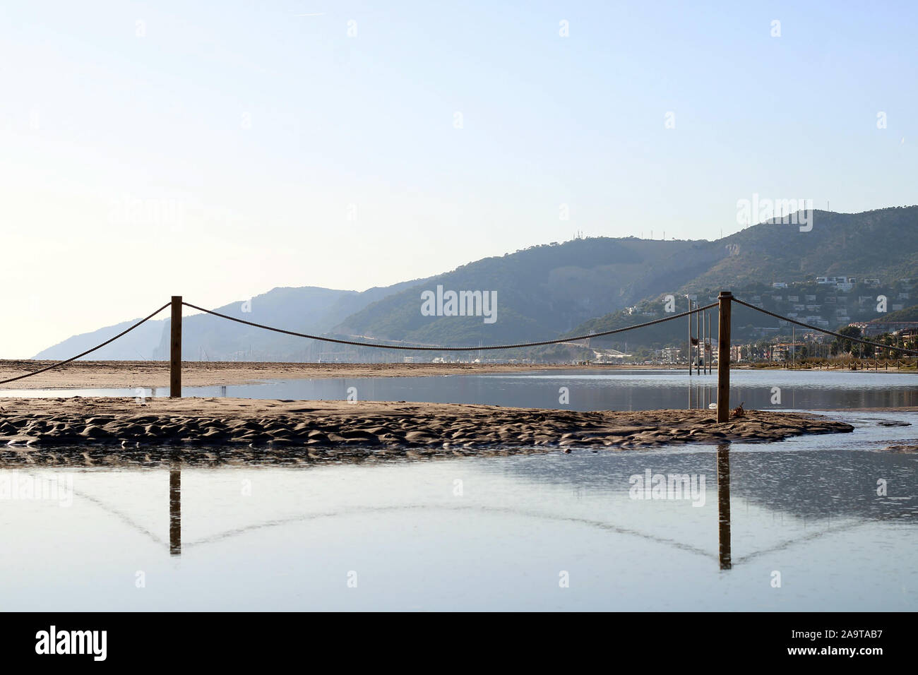 Lake with a railing in the middle that is reflected in the water. Mountains in the background. Neutral colors. Winter landscapes. Stock Photo