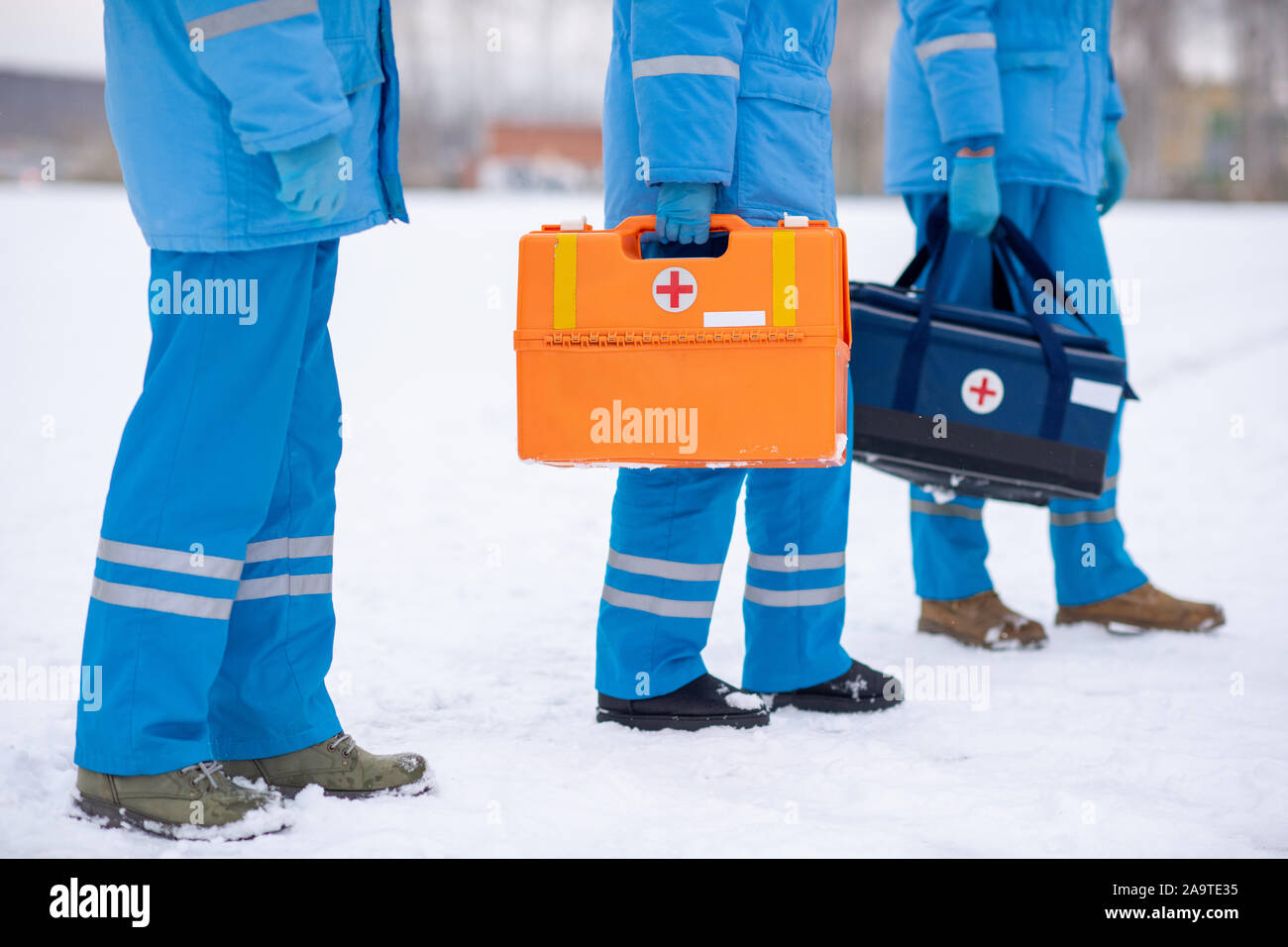 Low section of paramedics in blue uniform and gloves holding first aid kits Stock Photo