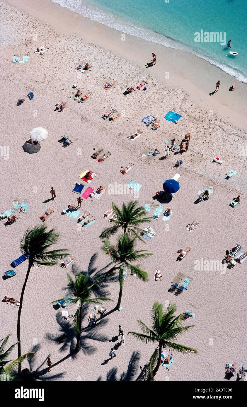 Sunbathers stretch out on the white sands of famous Waikiki Beach that ...