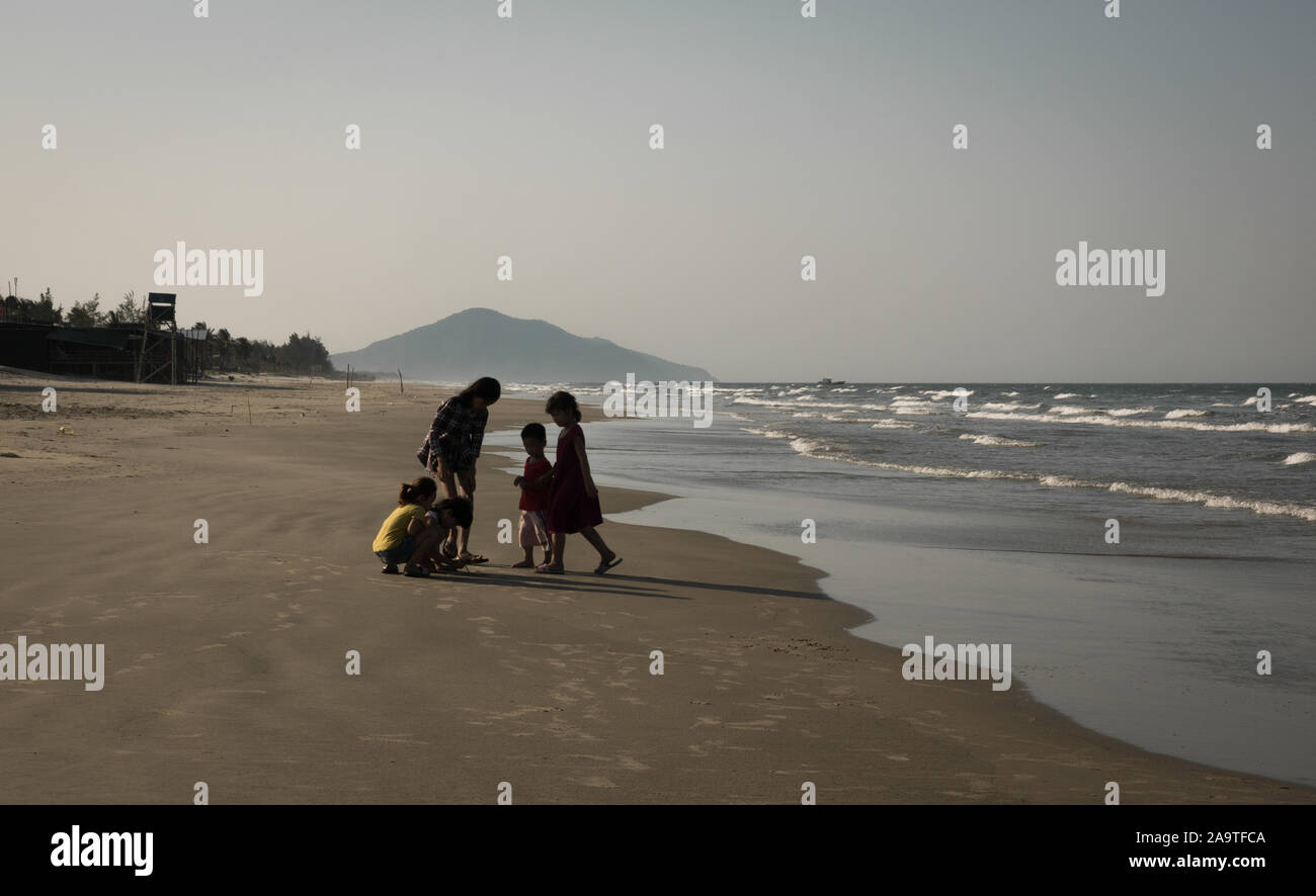 Young Vietnamese children playing together at wide and empty Lang Co beach, Vietnam Stock Photo