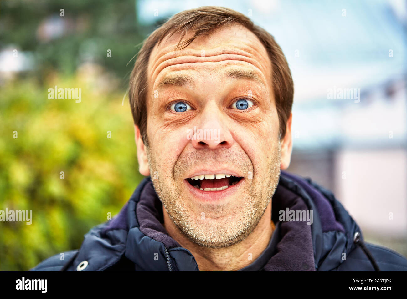 The surprised face of a man of fifty years old against the background of a European street, close-up. Head of a joyful middle-aged male over 50 outdoo Stock Photo
