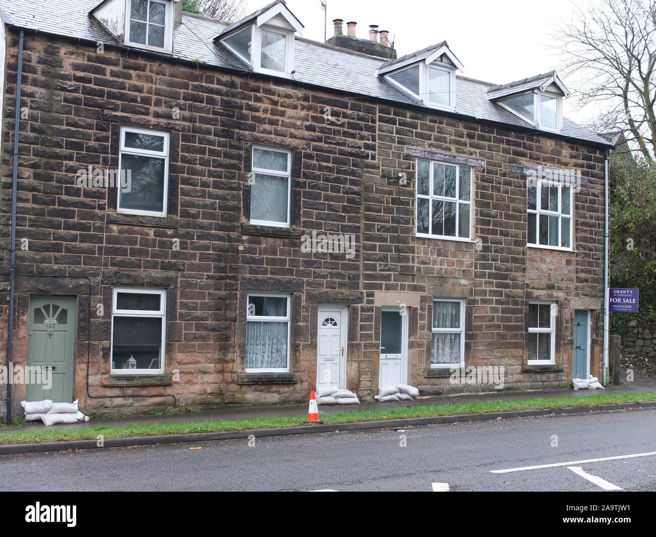 Terraced houses including one for sale at Matlock Derbyshire with sandbags piled up outside front doors the week after heavy flooding in November 2019 Stock Photo