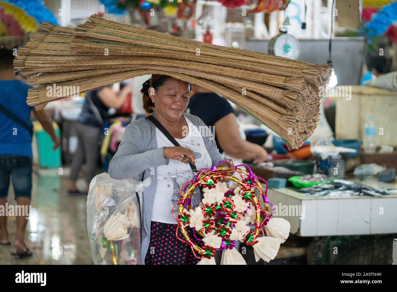 A woman carrying handwoven mats known as a Banig,a type of sleeping mat