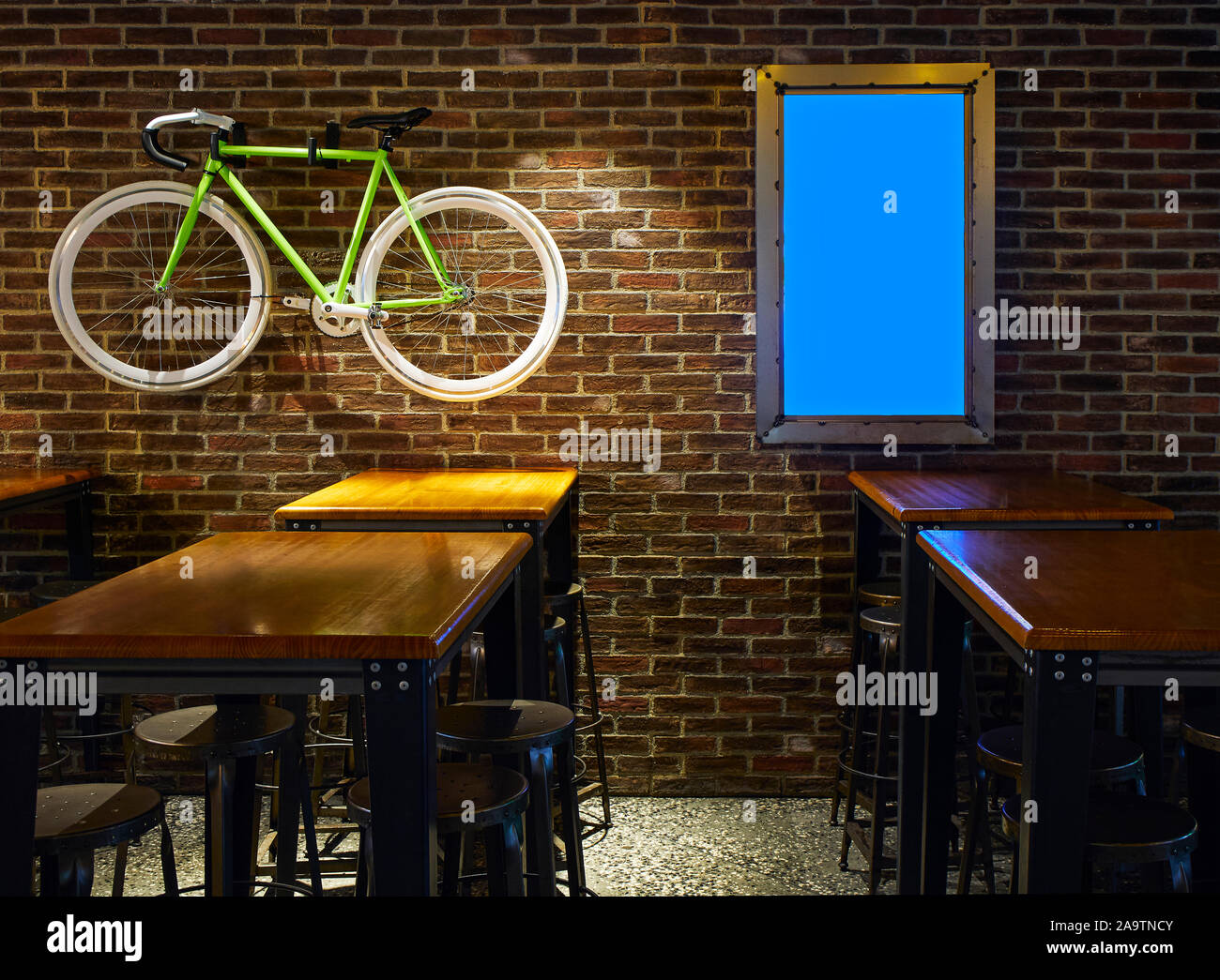 Dining room of an Industrial style Restaurant with a Blank Display and a Modern bicycle on a Brick Wall. Stock Photo