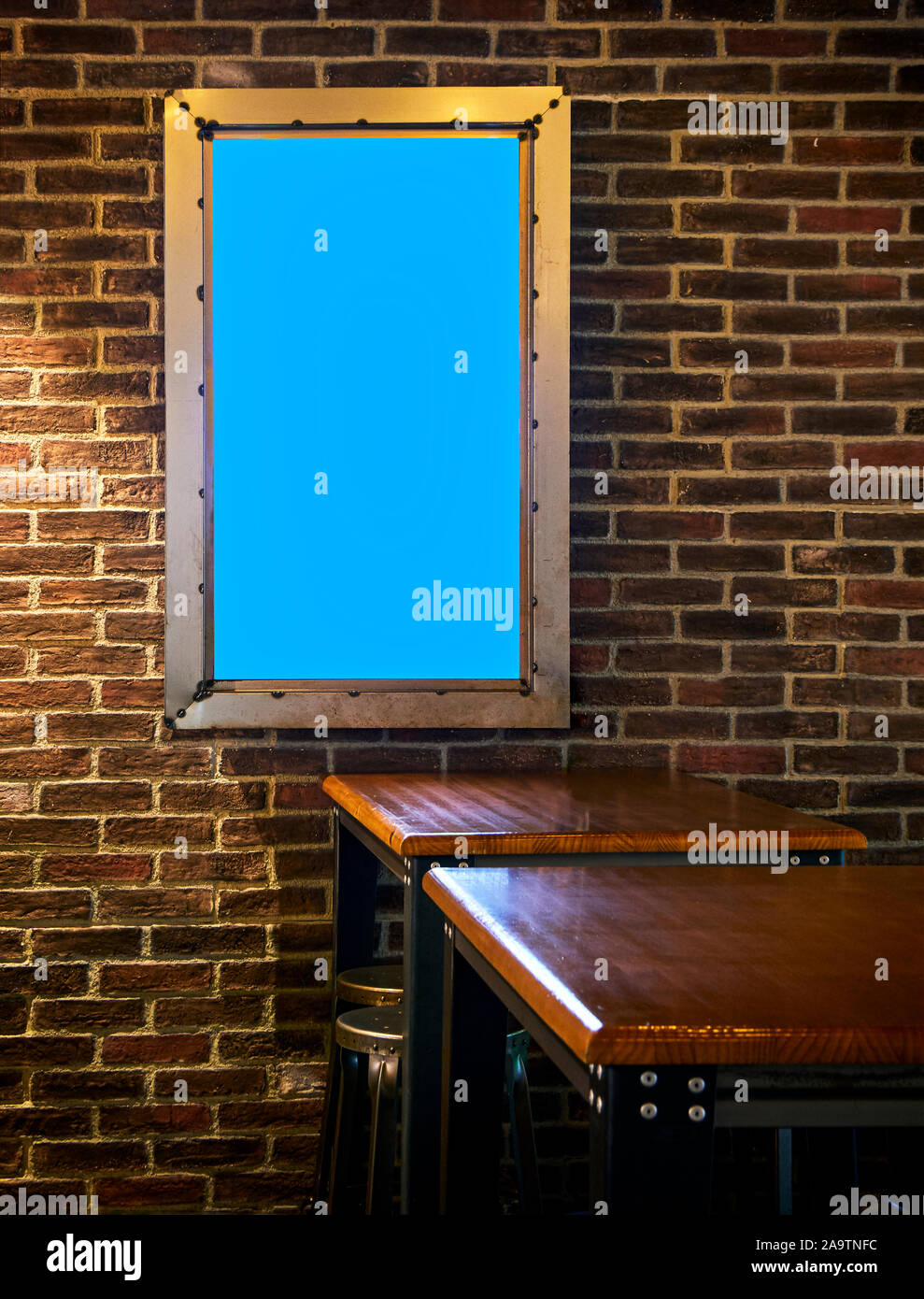 Dining room of an Industrial style Restaurant with a Blank Display on a Brick Wall. Stock Photo