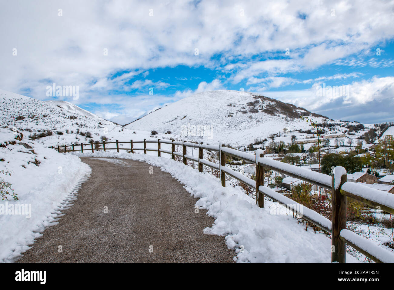 Winter country landscape with timber fence and road into snowy forest ...