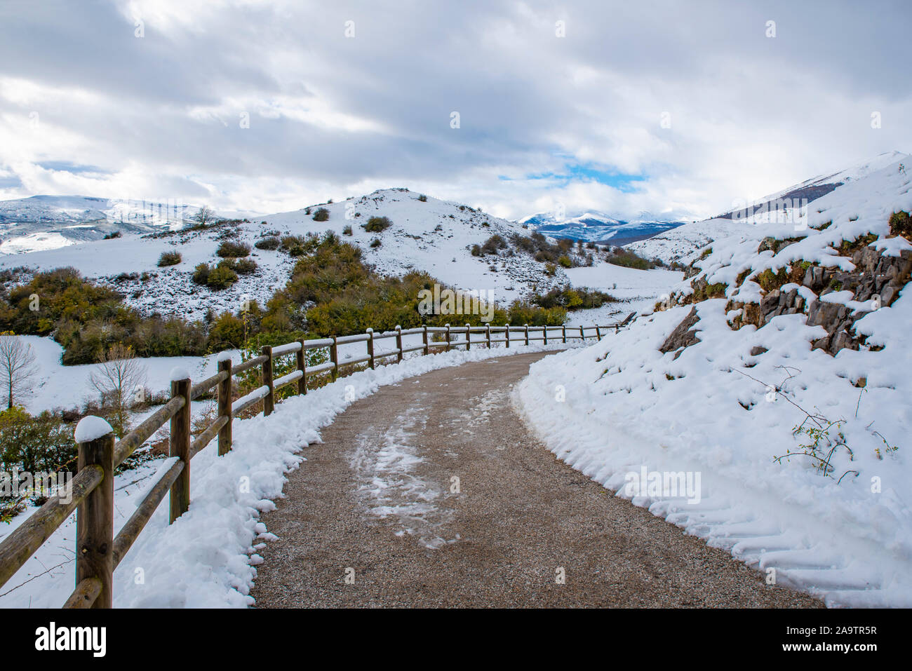 Winter country landscape with timber fence and road into snowy forest ...