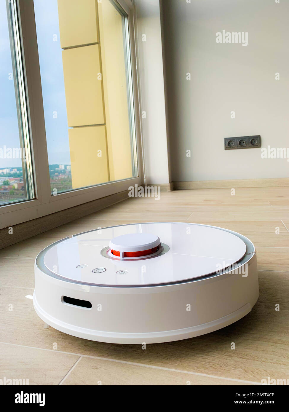 White robot cleaner. Robot vacuum cleaner on laminate floor in action ...