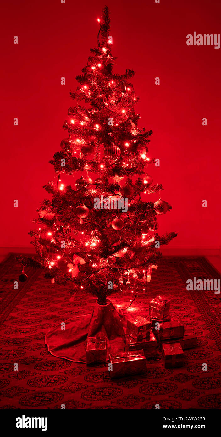 Christmas tree with red lights and christmas present under the xmas tree. Shiny christmas ornaments are glittering on the tree. Stock Photo