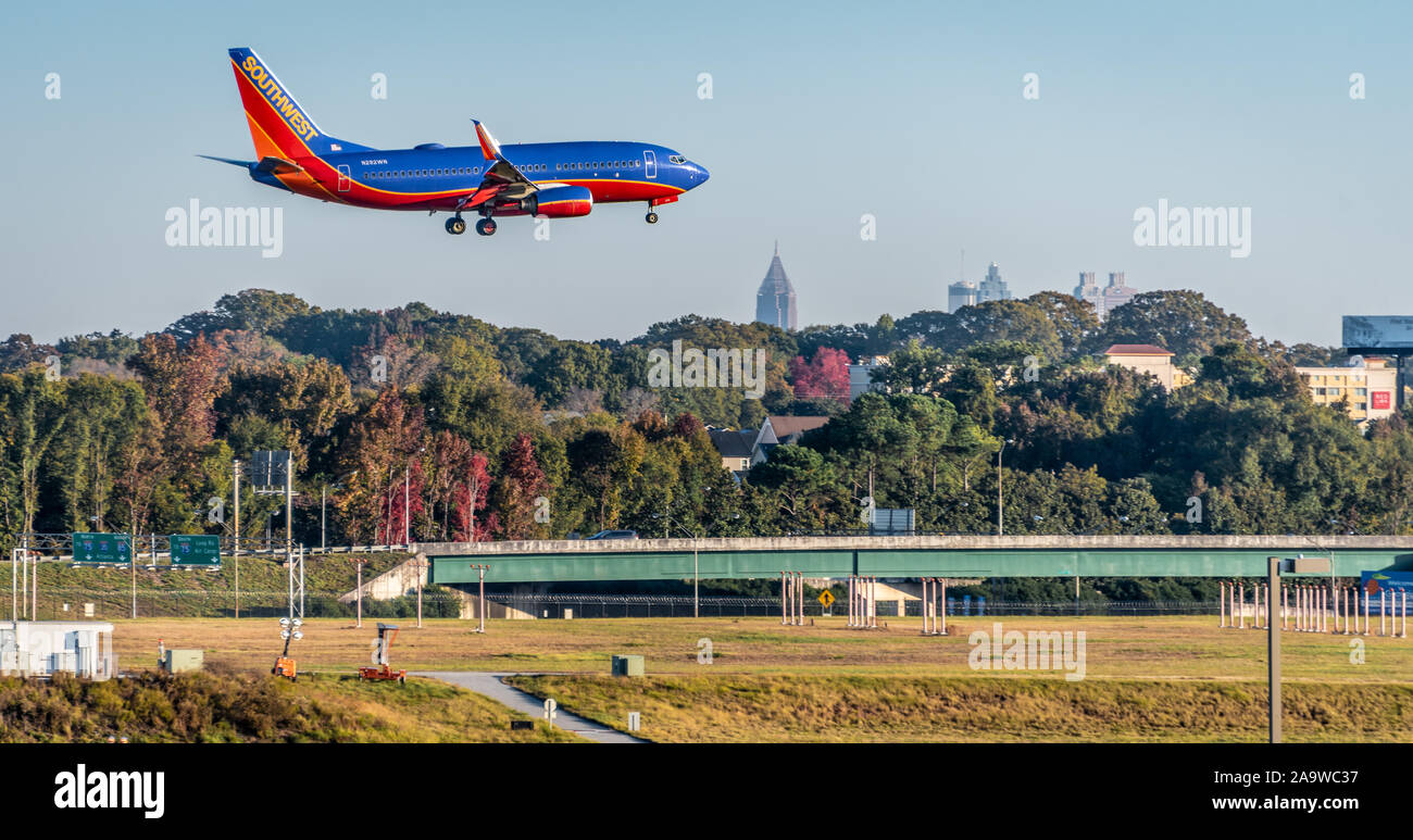 Southwest Airlines jet landing at Hartsfield-Jackson Atlanta International Airport with Downtown Atlanta city skyline visible in the distance. (USA) Stock Photo