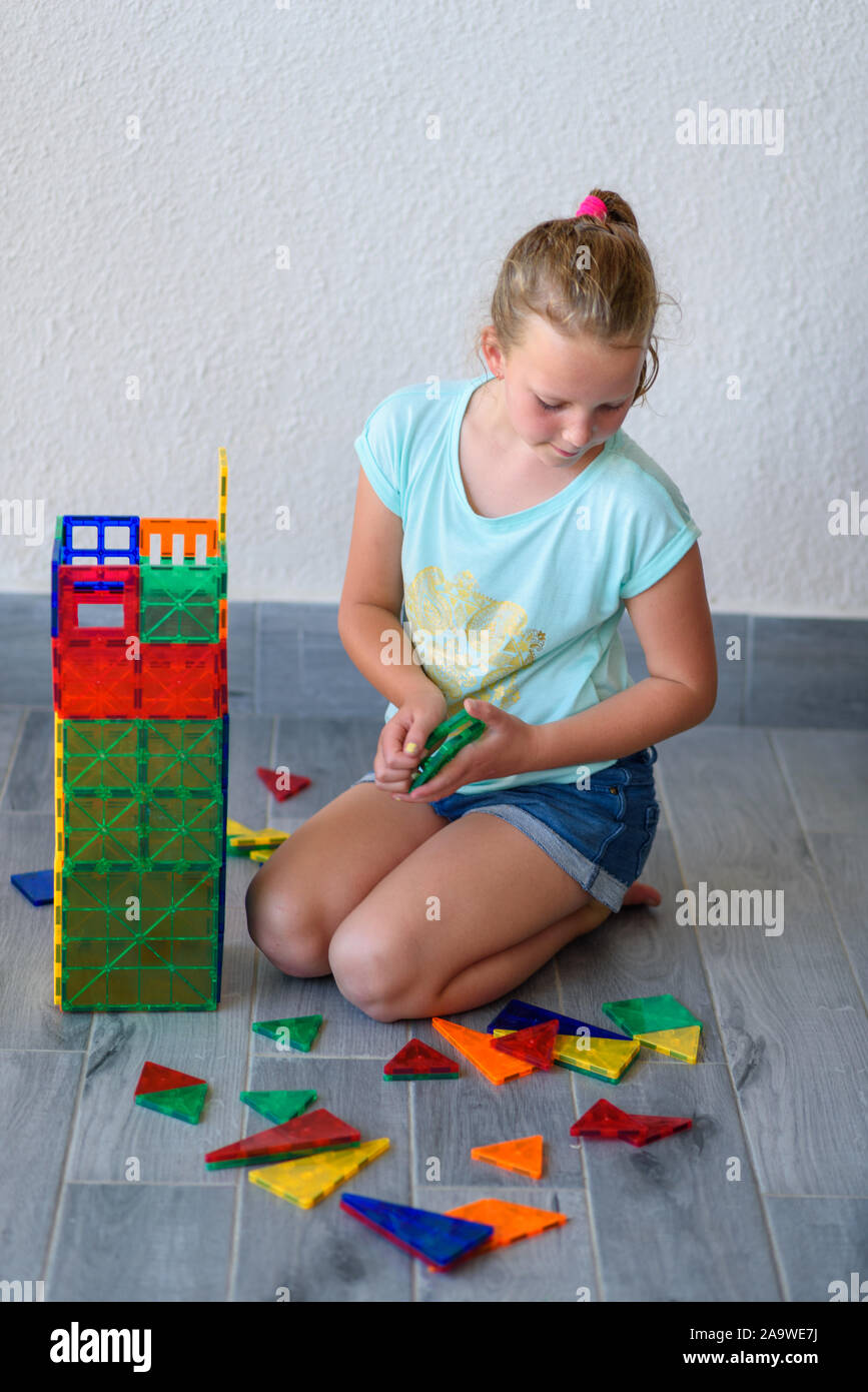 Beautiful teenage girl playing with lots of colorful plastic blocks ...