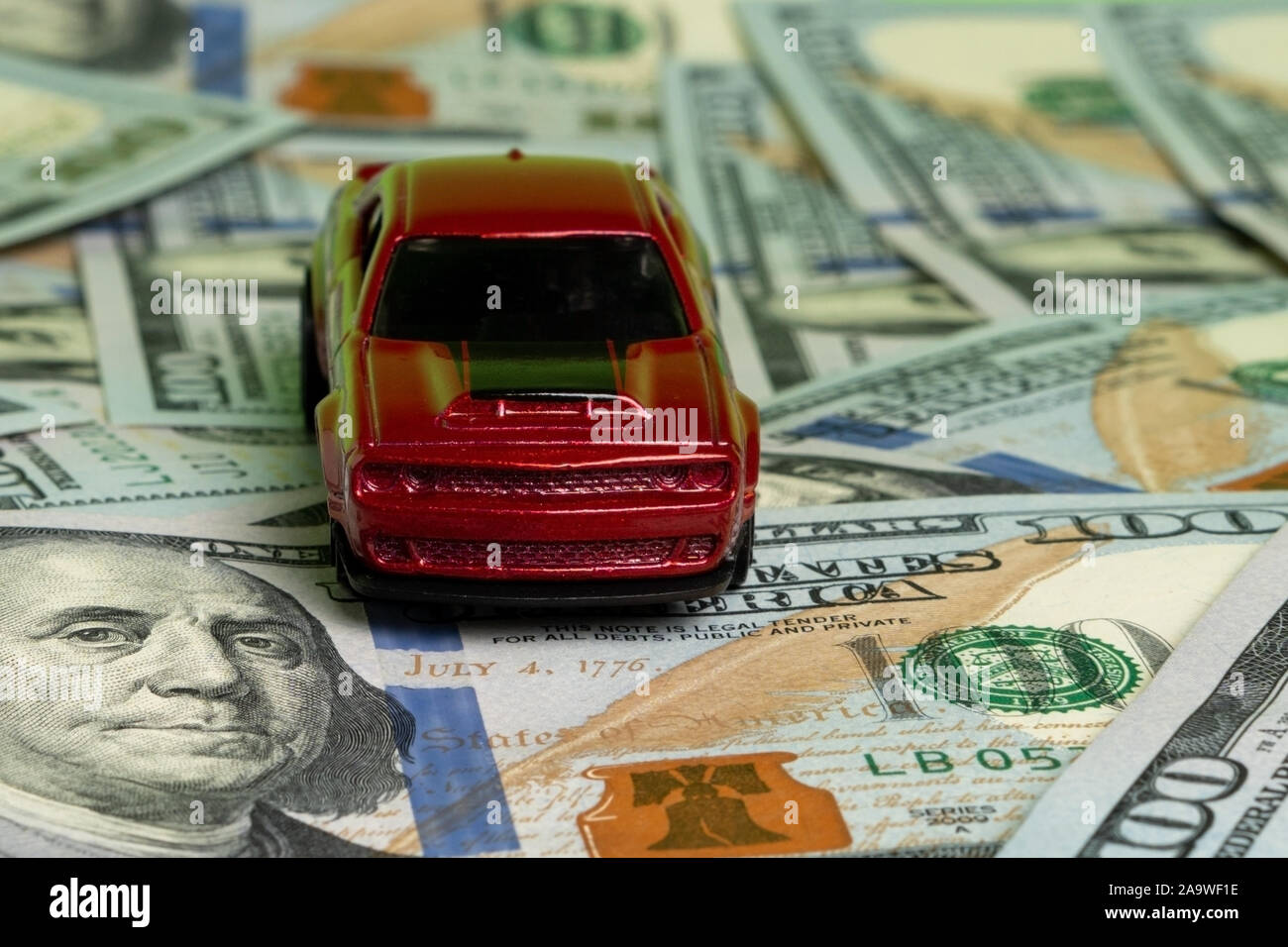 Red toy car on hundred dollar bills close up Stock Photo - Alamy