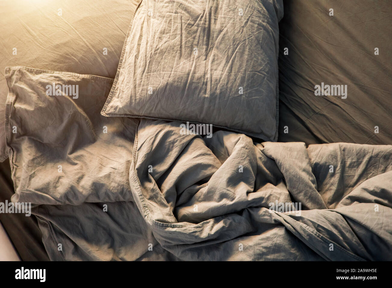 A gray cotton sheet and blankets with pillows on the bed Stock Photo