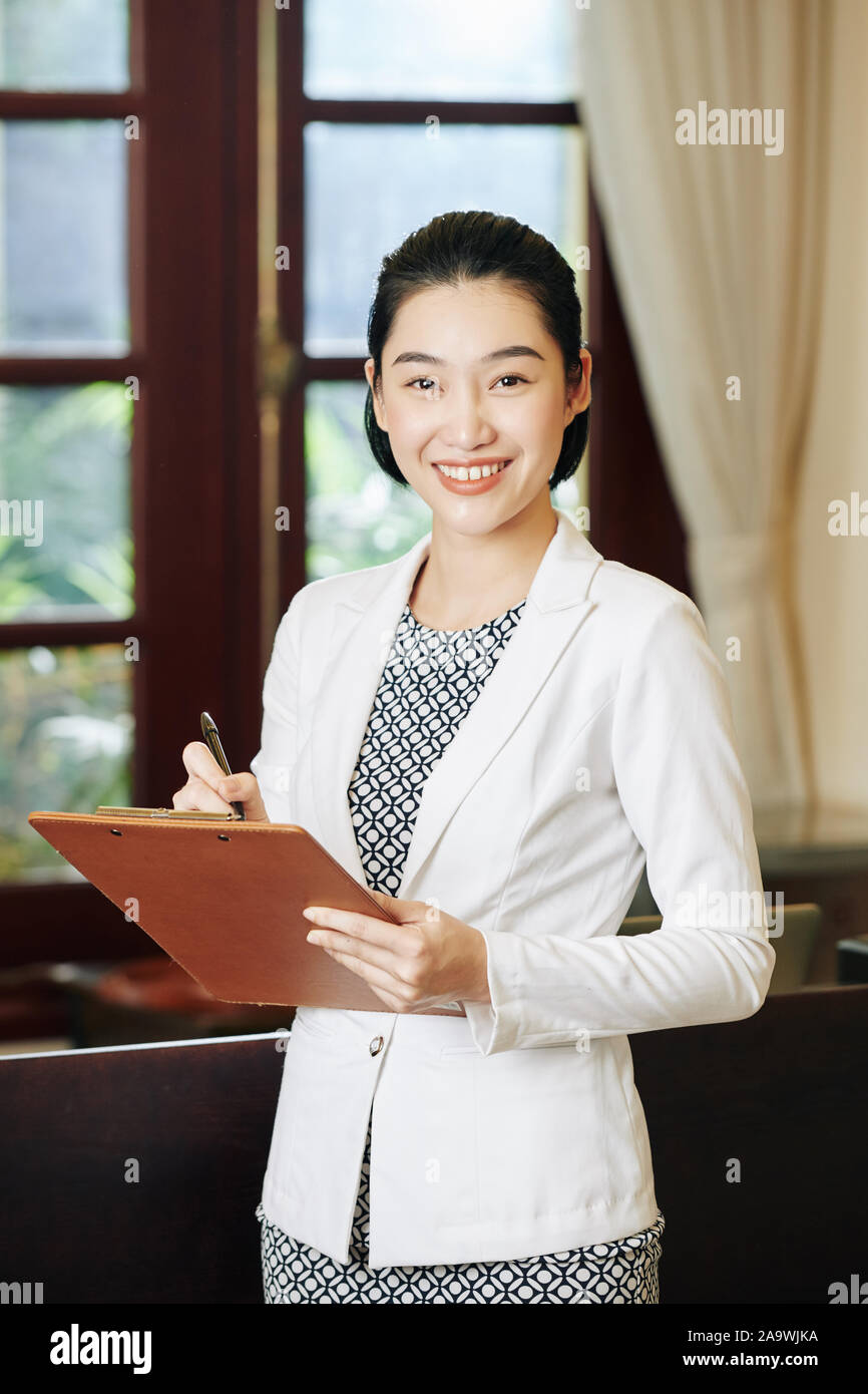 Positive pretty spa salon manager checking list of clients for the day