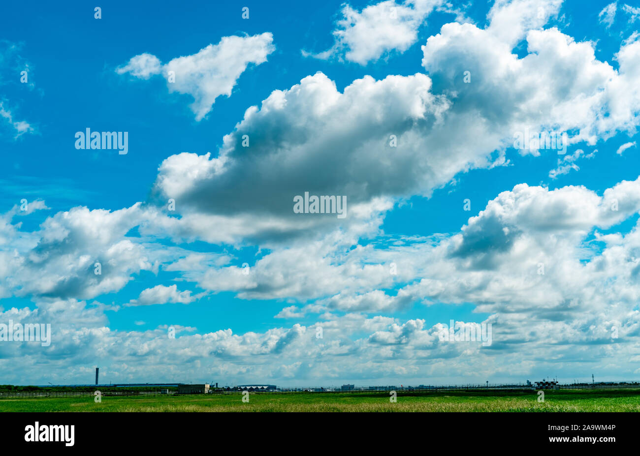 Landscape green grass field and wire fence of the airport and beautiful blue sky and white fluffy clouds. Nice weather. Nature landscape. Area around Stock Photo