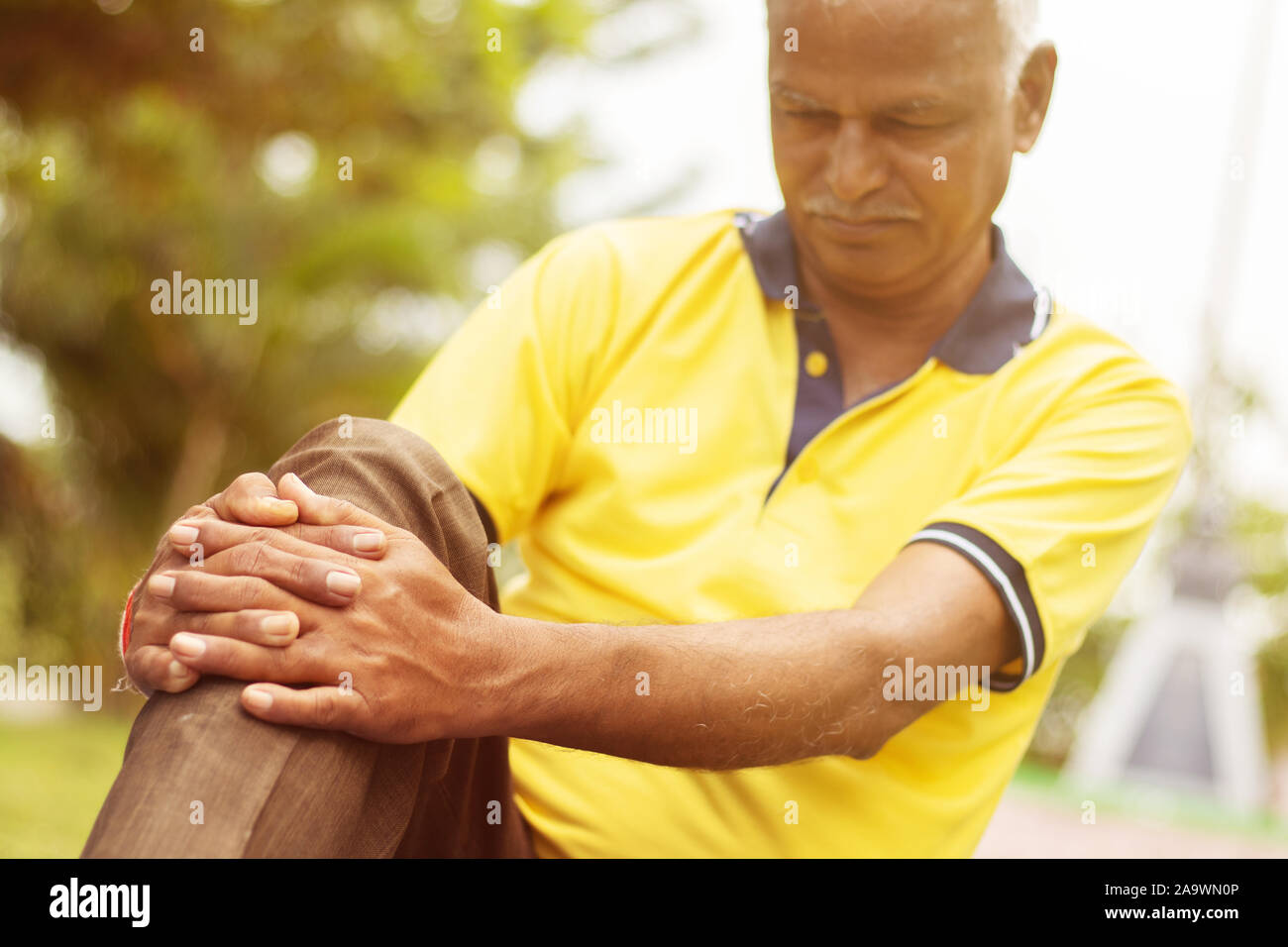 Elderly man having a knee injury - Concept Senior Man fitness and yoga at outdoor - Selective focucs on hand, old man holding knee due to pain. Stock Photo