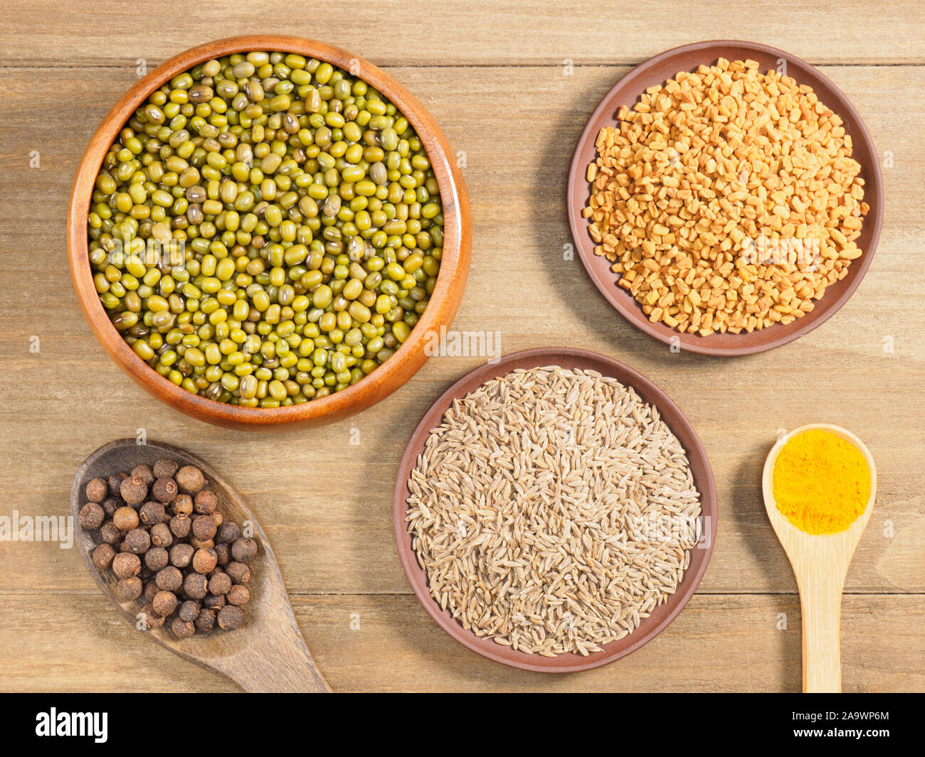 Allspice, mung bean, turmeric, fenugreek, cumin on brown wooden