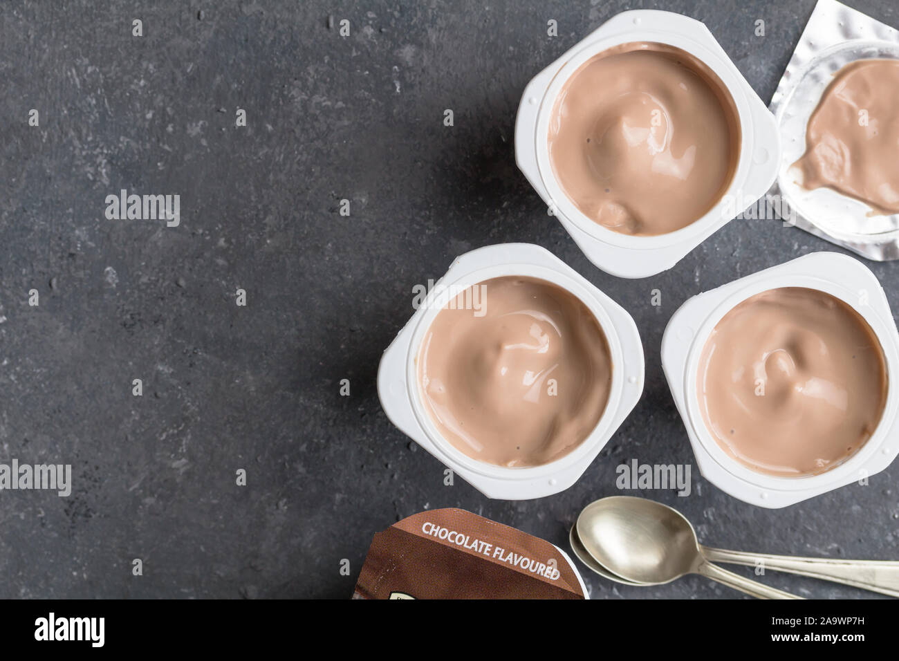 Chocolate yogurt cups on black mottled background with small silver