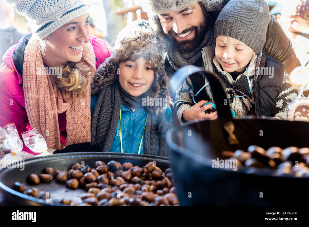 Family on Christmas market eating sweet roasted chestnuts Stock Photo