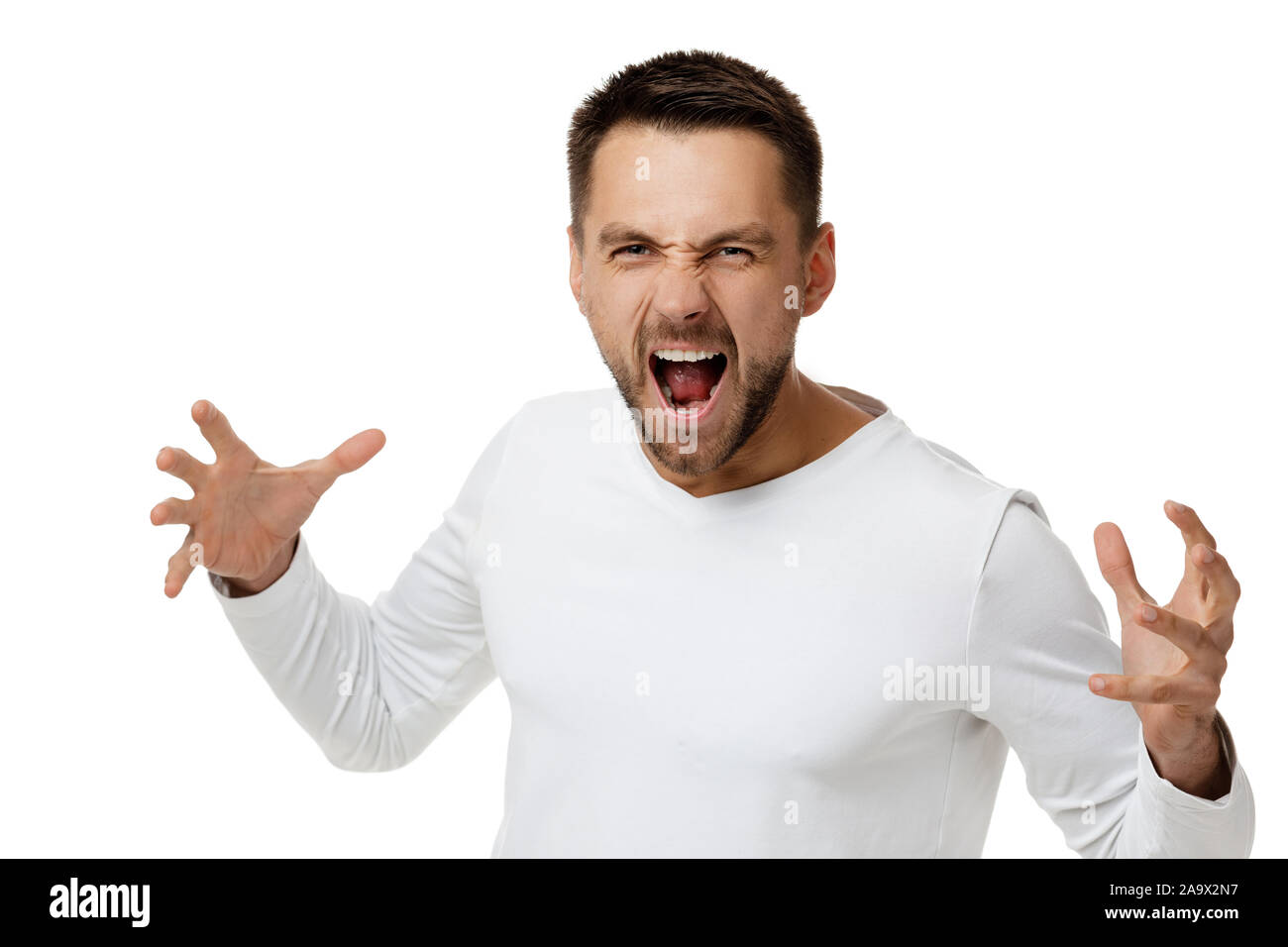 portrait of furious enraged bearded man in casual white shirt shouting and screaming isolated on white background Stock Photo