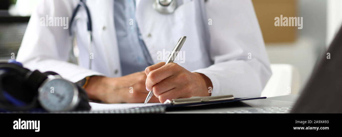 Hands of female GP making notes with silver pen Stock Photo