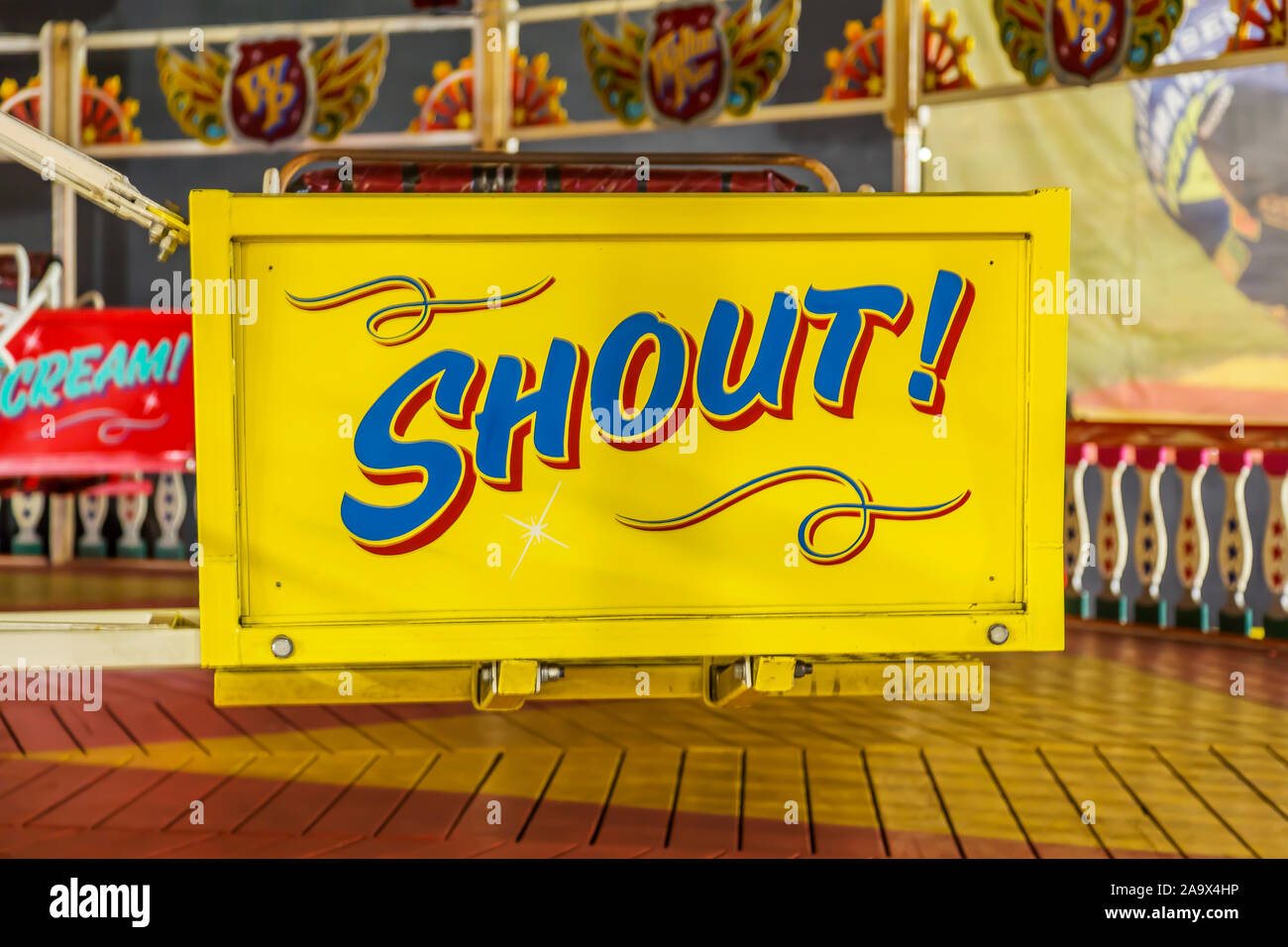 A brightly coloured hand painted fairground ride sign of the word Shout. Possible concept uses hearing loss, anger, activism, making yourself heard. Stock Photo