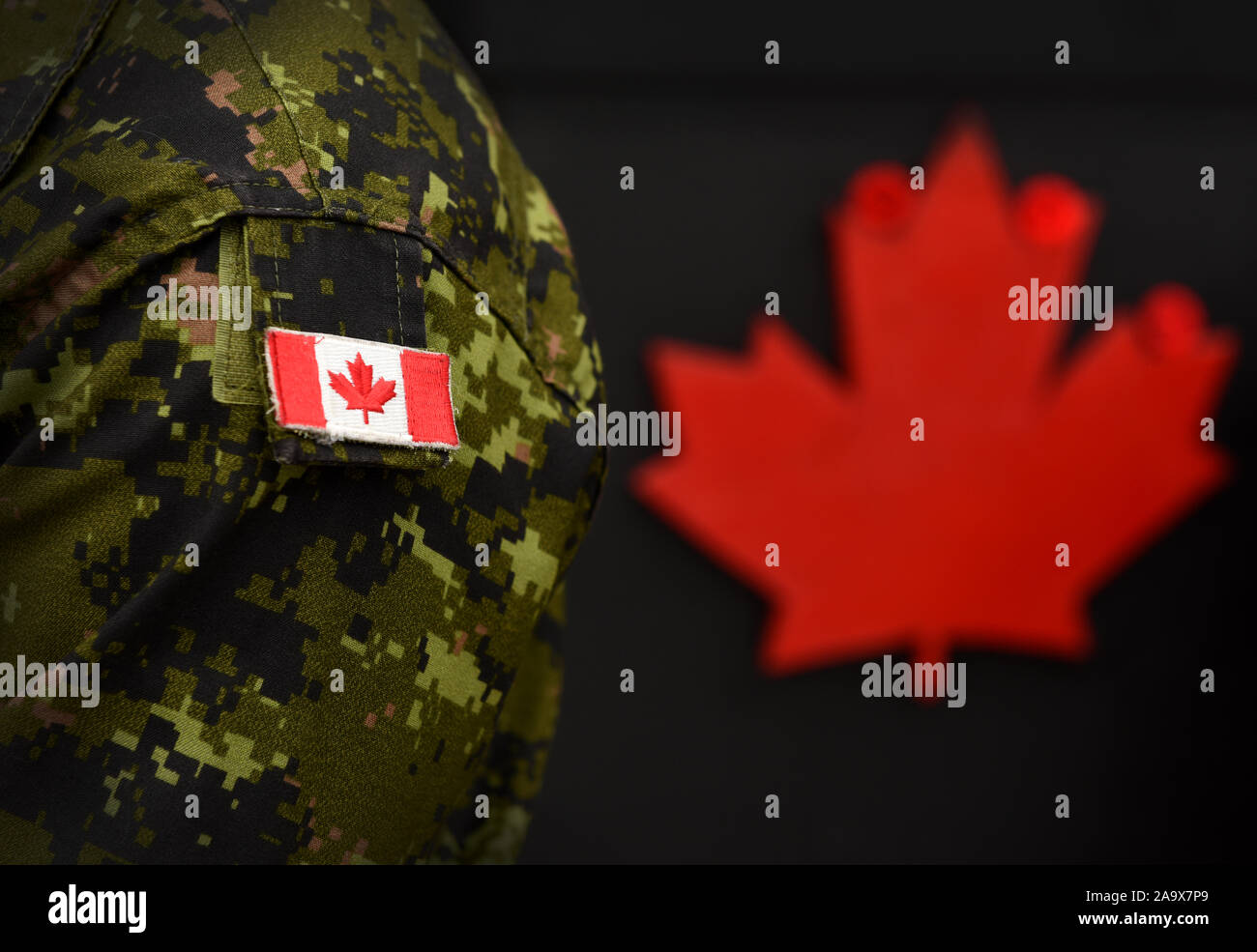 Canada Day. Flag of Canada on the military uniform and red Maple leaf on the background. Canadian soldiers. Army of Canada. Canada leaf. Remembrance D Stock Photo