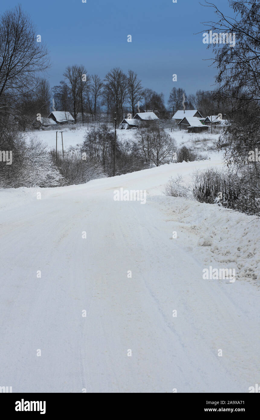 Winter landscape with road leading to village houses with snow covered ...