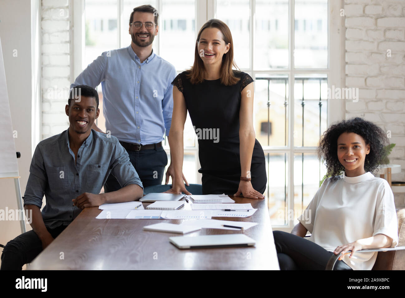 Joyful millennial diverse professionals gathered near table. Stock Photo