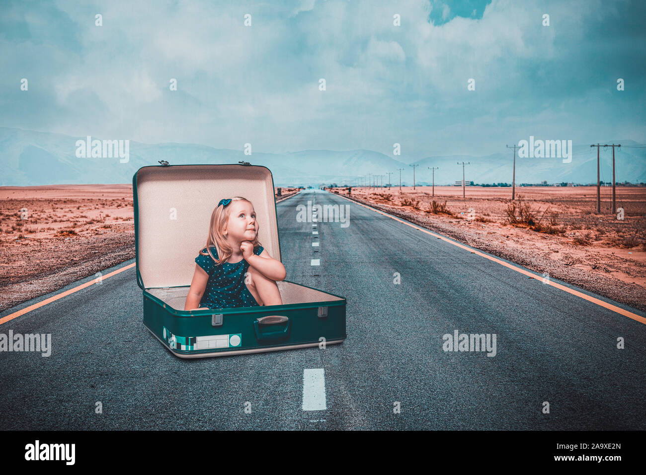 little girl sitting in an old suitcase on a road dreams of an adventure. Travel and freedom concept. Stock Photo