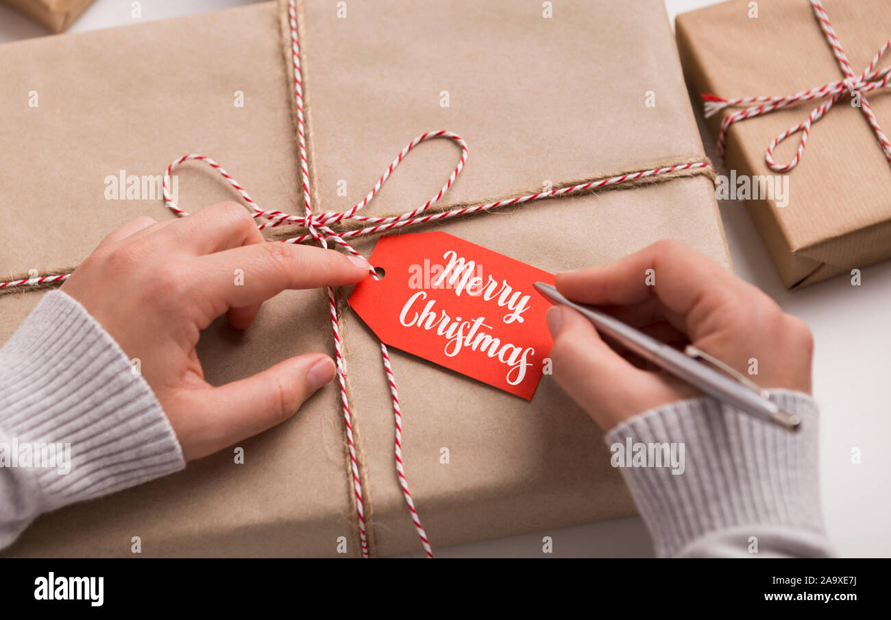 Woman writing Merry Christmas text on red label Stock Photo