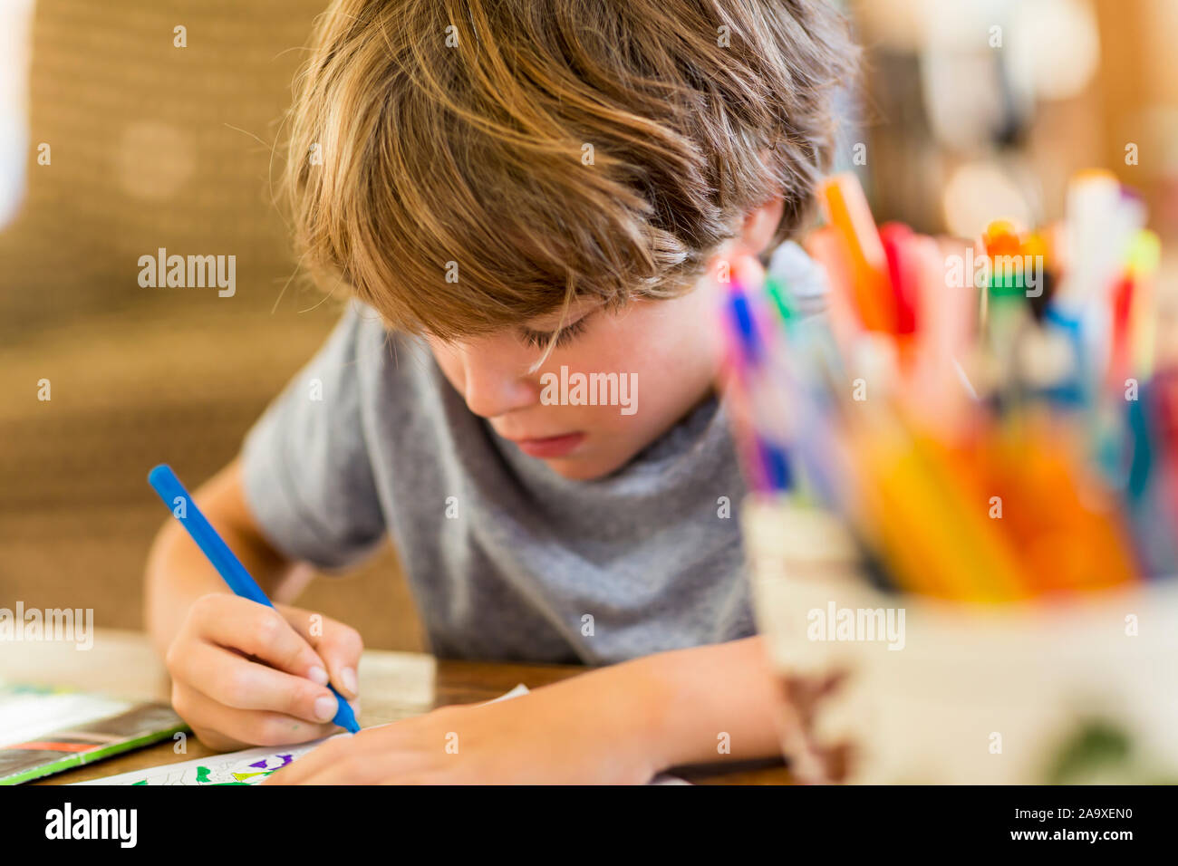 6 year old boy drawing amoung colorful pens Stock Photo