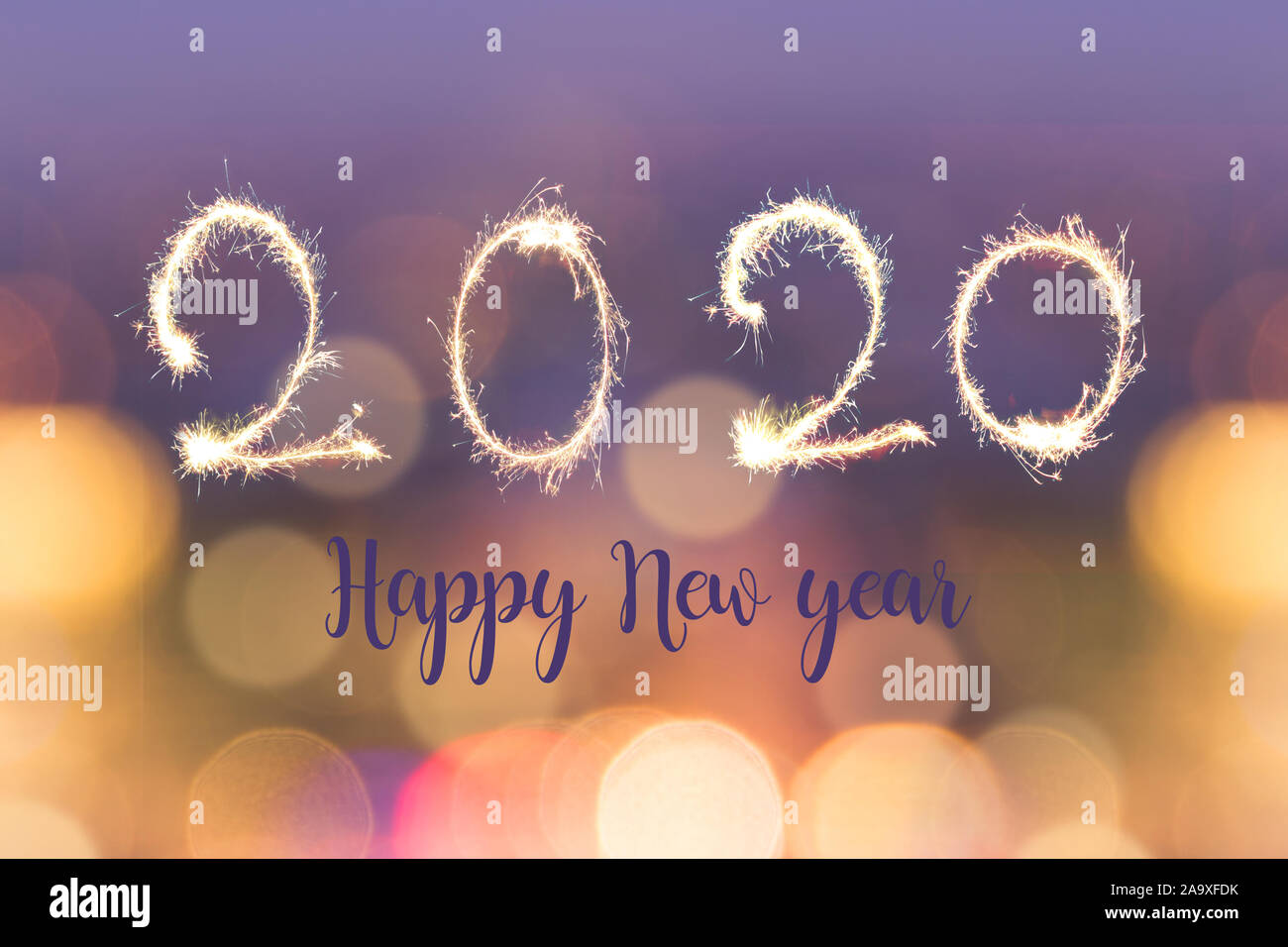 Happy new year 2020 written with sparkes on blurred bokeh lights background, holiday greeting card Stock Photo