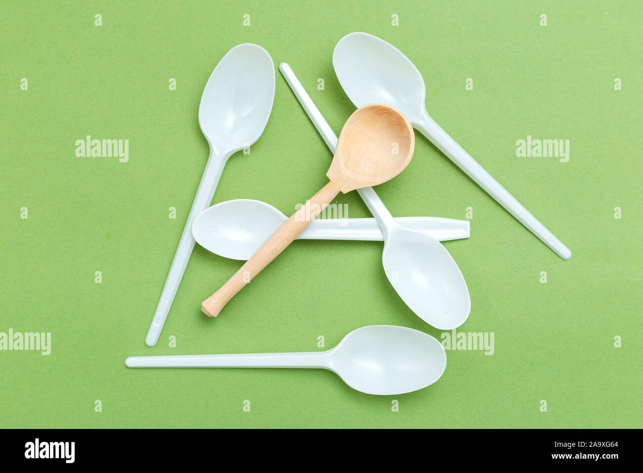 Alternative wooden spoon versus plastic on green background. Flat lay