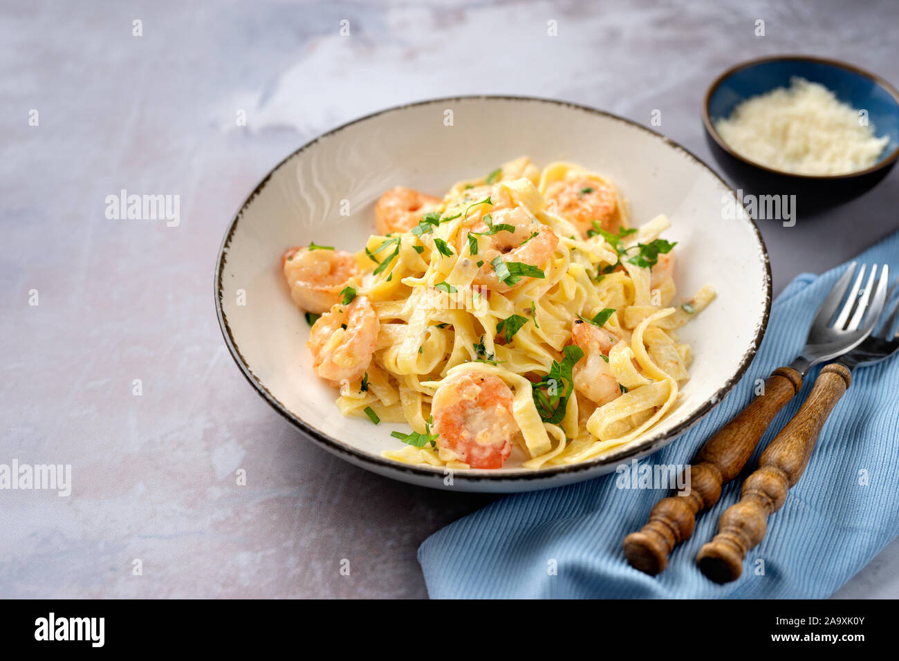 Tasty shrimp fettuccine alfredo with parmesan on light blue background Stock Photo Alamy