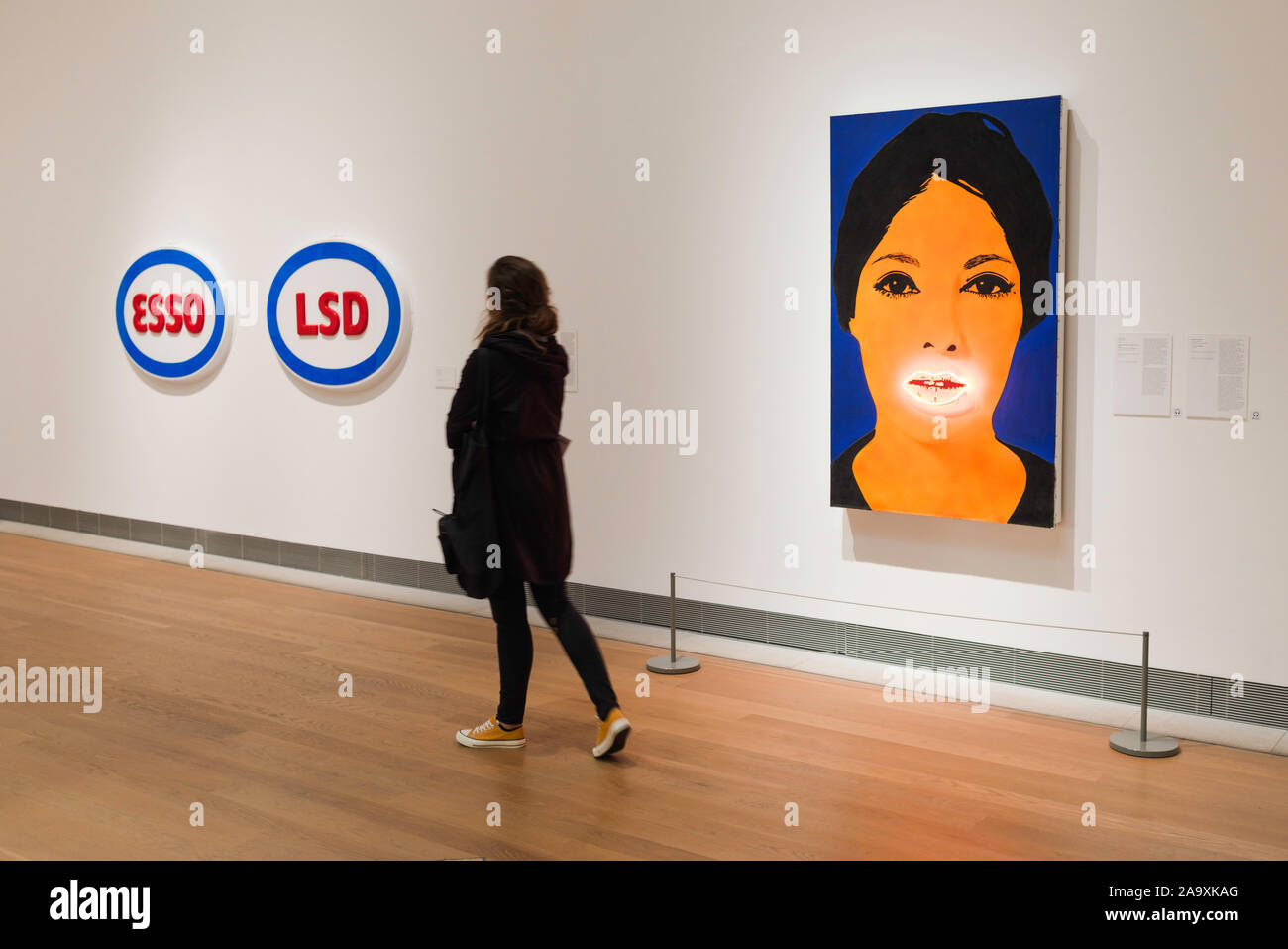 Woman art, a young woman walks past works by Elaine Sturtevant (High Voltage Painting) and Öyvind Fahlström (ESSO LSD), Moderna Museet, Stockholm. Stock Photo
