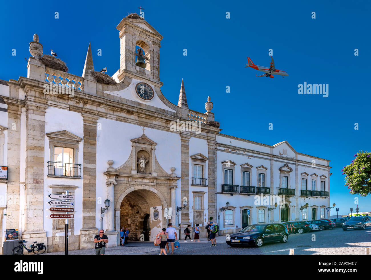 Passenger jet flying over Faro landmark, Arco da Vila coming into land at Faro airport, Faro, Algarve, Portugal. Stock Photo