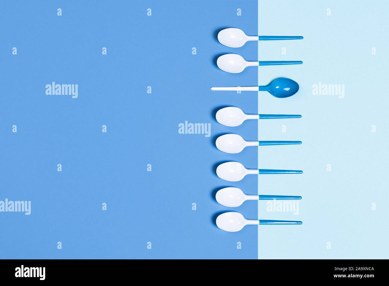 Beautiful and dangerous plastic spoons on twotoned blue background