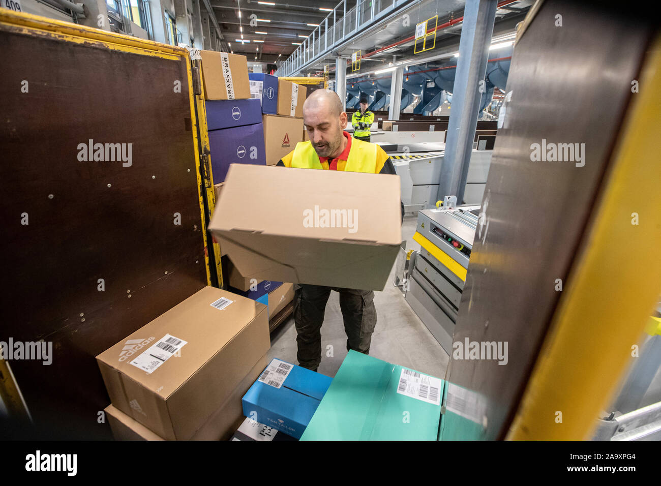 Bochum, Germany. 18th Nov, 2019. Delivery driver Franko places a parcel in  a transport cart. Deutsche Post DHL has opened a new parcel centre on the  former Opel site. With a sorting