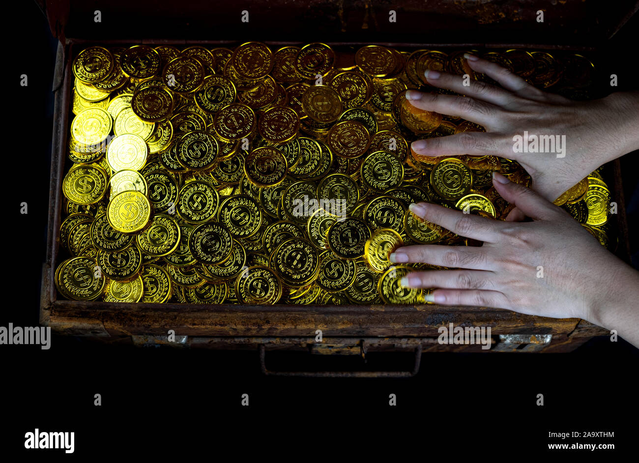 Lots of stacking Gold Coin in lady hand and treasure chest at black