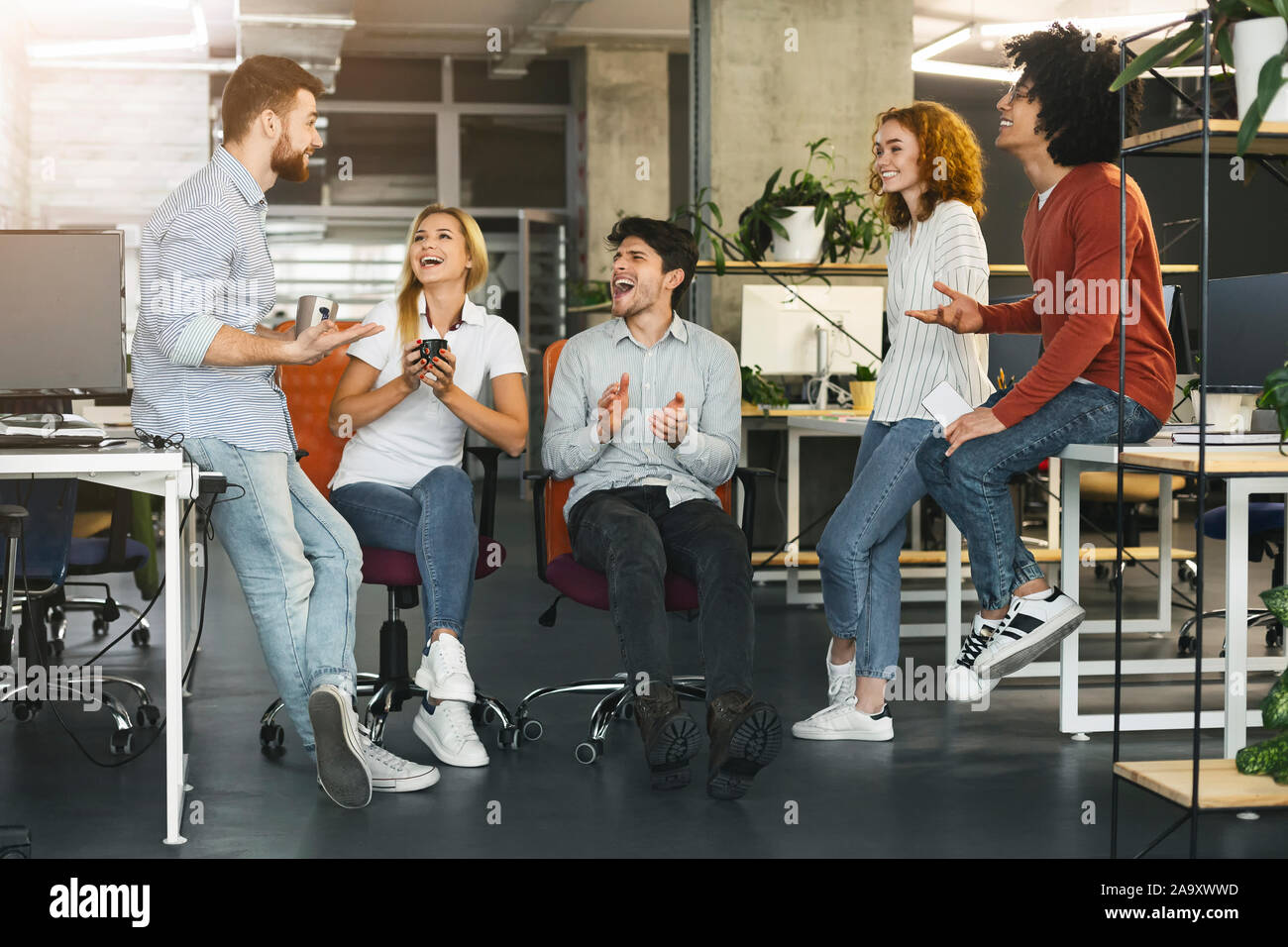 Young coworkers having pleasant talk in office Stock Photo
