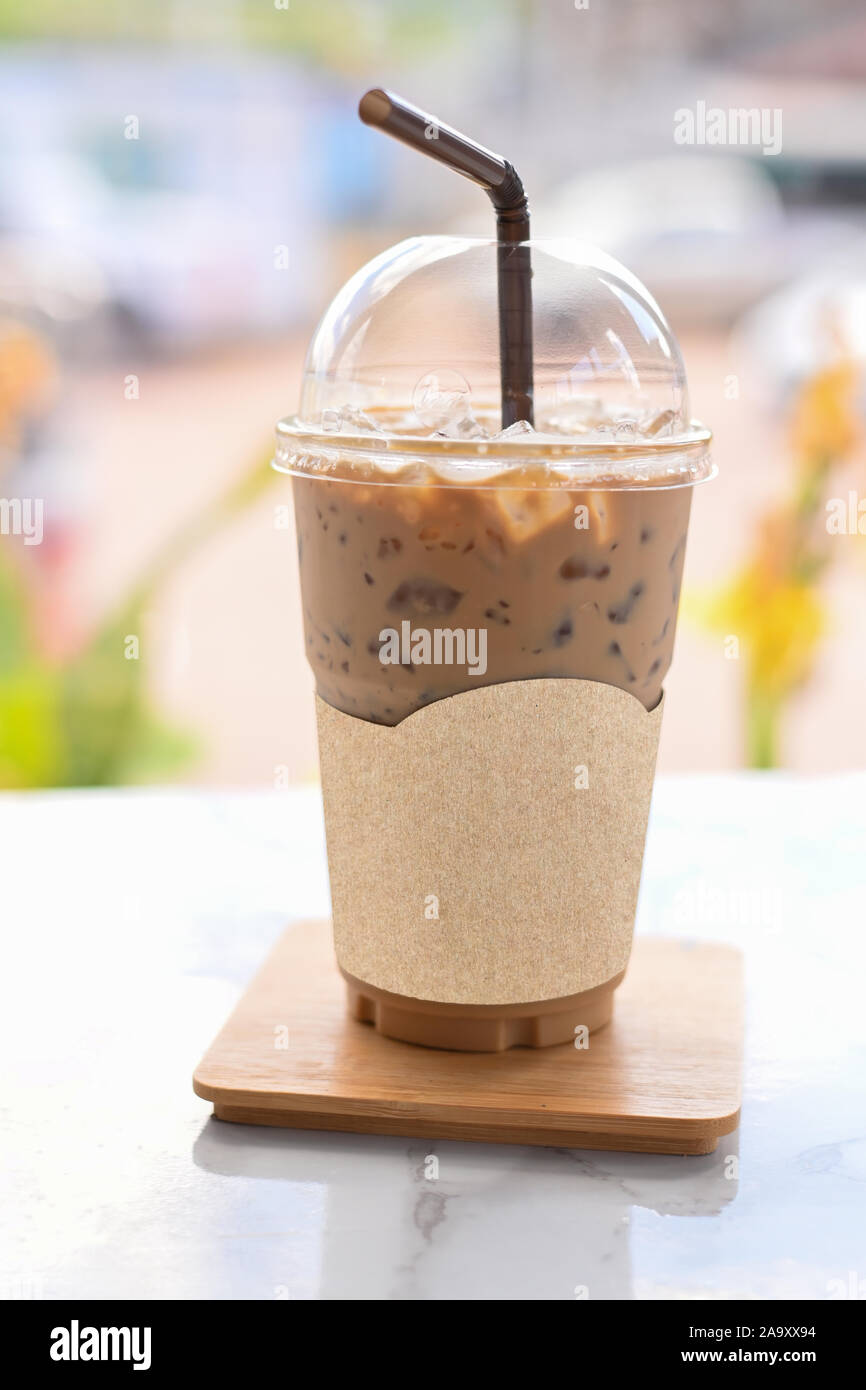 Iced coffee in take away cup plastic glass on the wood table in cafe with  clipping path on blank label paper for mockup cafe logo Stock Photo - Alamy