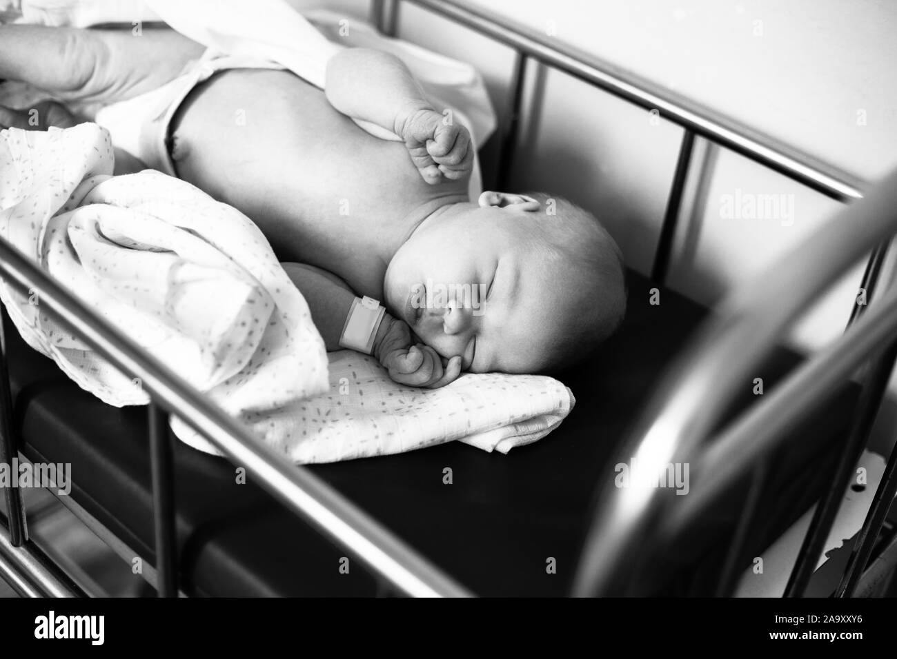 Sleeping newborn resting in a hospital bed in the maternity ward of the hospital. Stock Photo