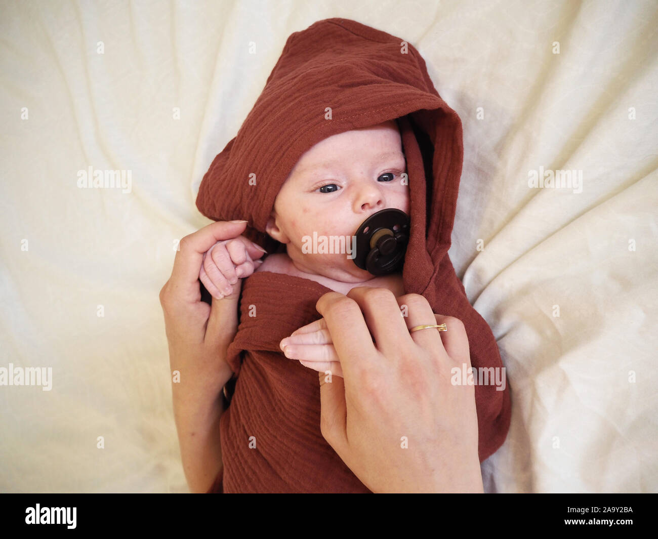Newborn Baby Care. Mothers Hand Comforting New Born Baby Boy Sleeping. Baby with Teat Stock Photo
