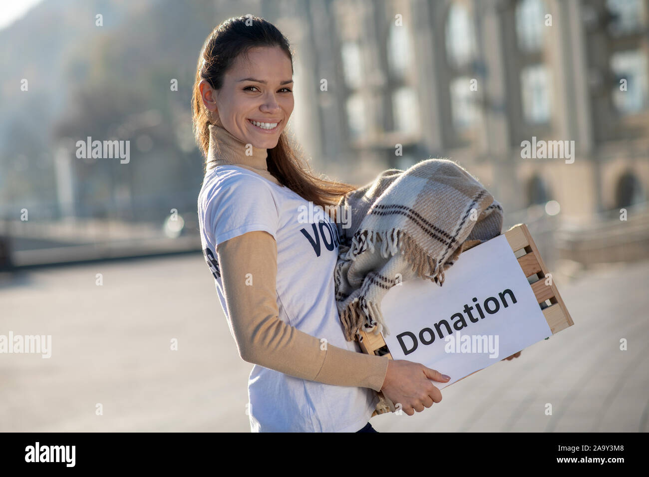 Volunteer feeling excited while caring box with old clothing Stock Photo