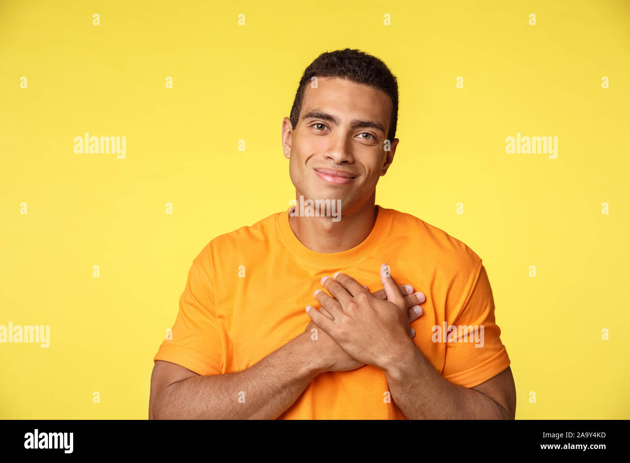 Pleased and touched young handsome romantice guy, receive nice heartwarming gift, touch heart and smiling delighted, receive new year, christmas Stock Photo