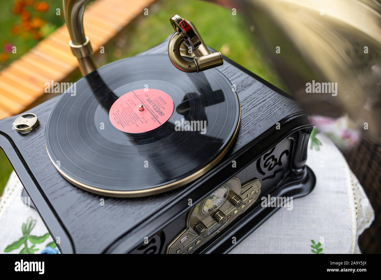 Vintage Retro Gramophone With Vinyl Record In The Summer Garden Playing vintage-retro-gramophone-with-vinyl-record-in-the-summer-garden-playing