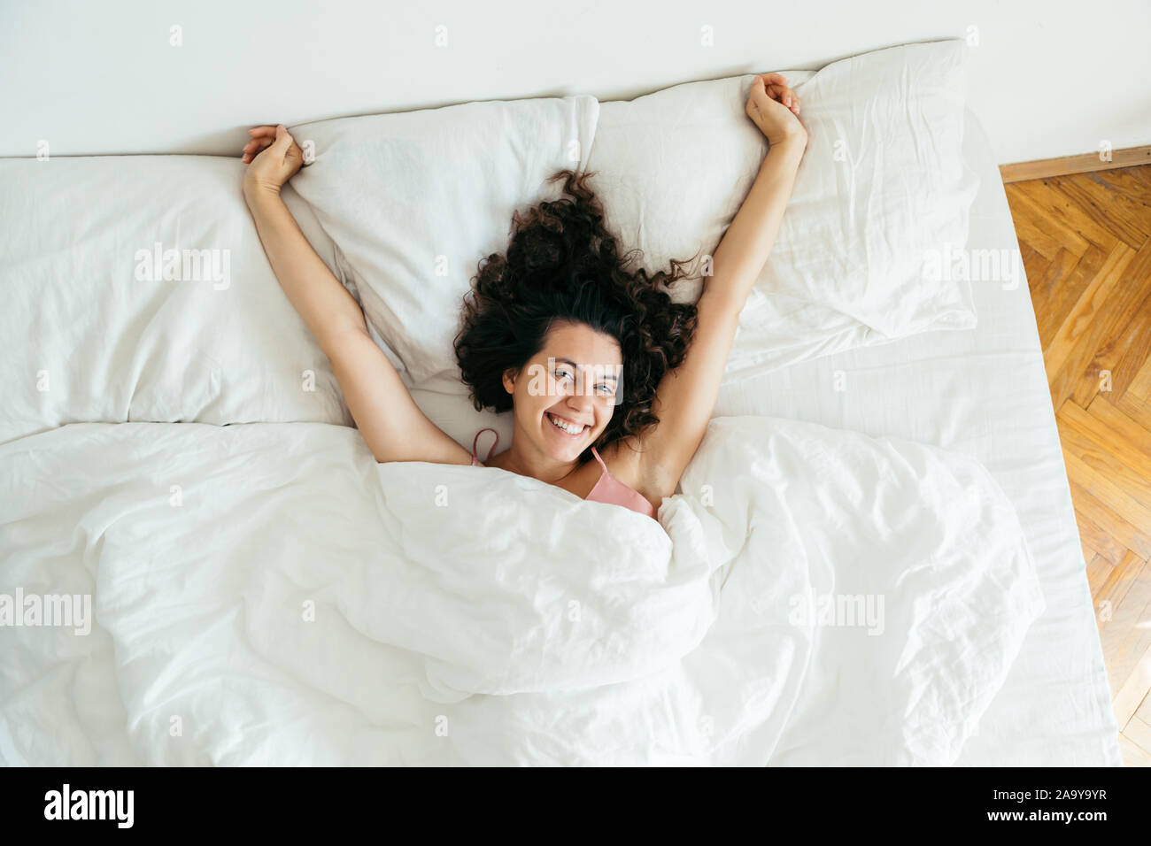 young pretty woman in bed with white sheets bright light Stock Photo