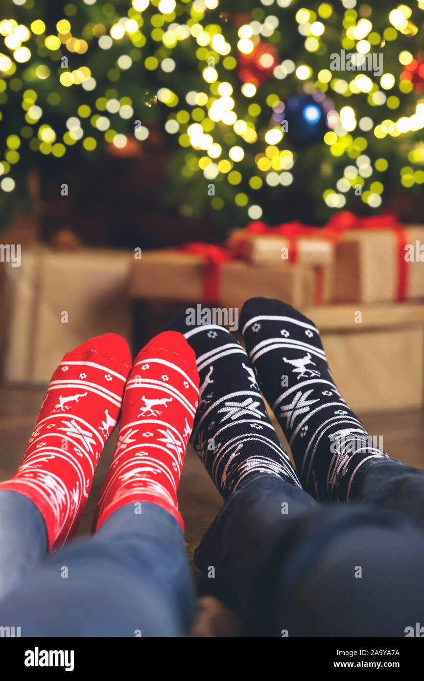 Closeup of couple's feet in Christmas socks near Xmas tree Stock Photo